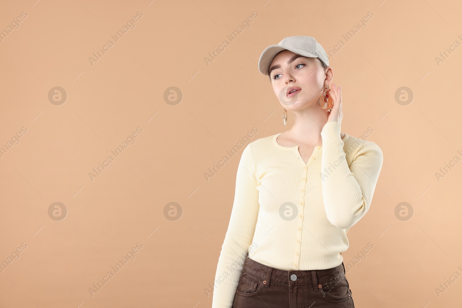 Beautiful woman in stylish baseball hat on beige background. Space for text Photo of Beautiful woman in stylish baseball hat on beige background. Space for text