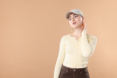 Photo of Beautiful woman in stylish baseball hat on beige background. Space for text