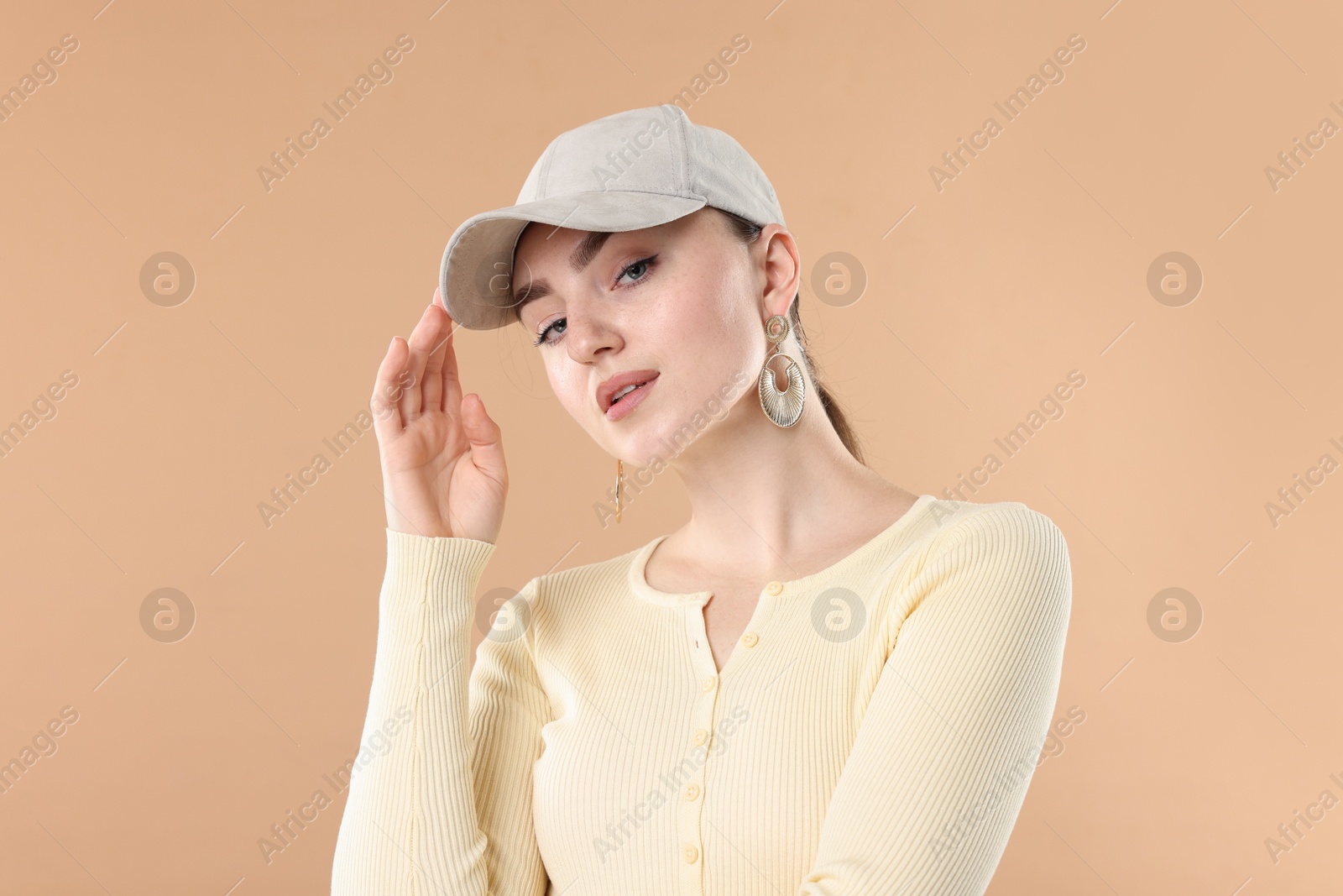 Portrait of beautiful woman in stylish baseball hat on beige background Photo of Portrait of beautiful woman in stylish baseball hat on beige background