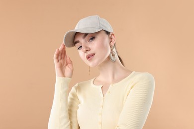 Photo of Portrait of beautiful woman in stylish baseball hat on beige background
