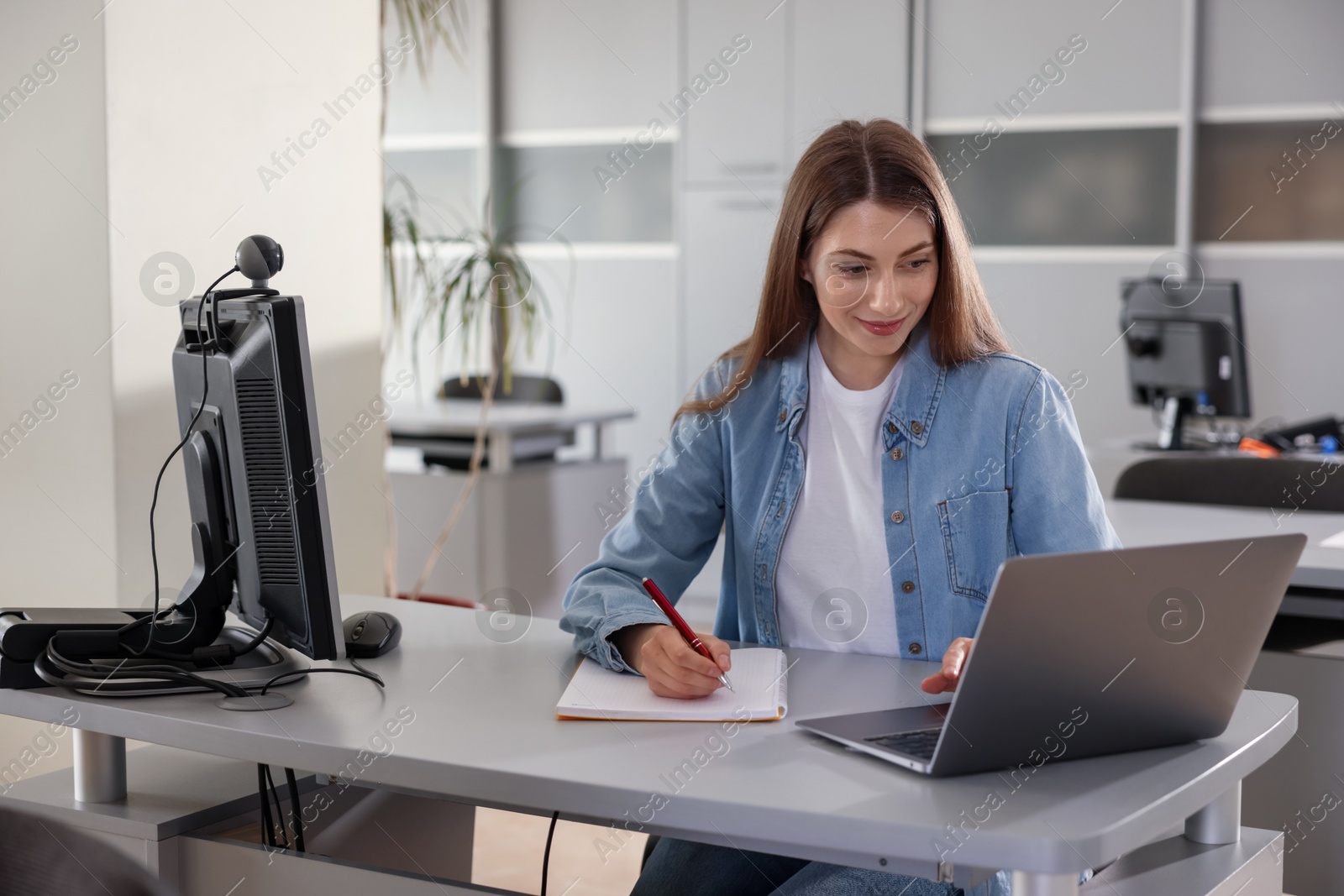 Woman working with laptop at desk in public library Photo of Woman working with laptop at desk in public library