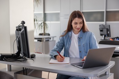 Photo of Woman working with laptop at desk in public library