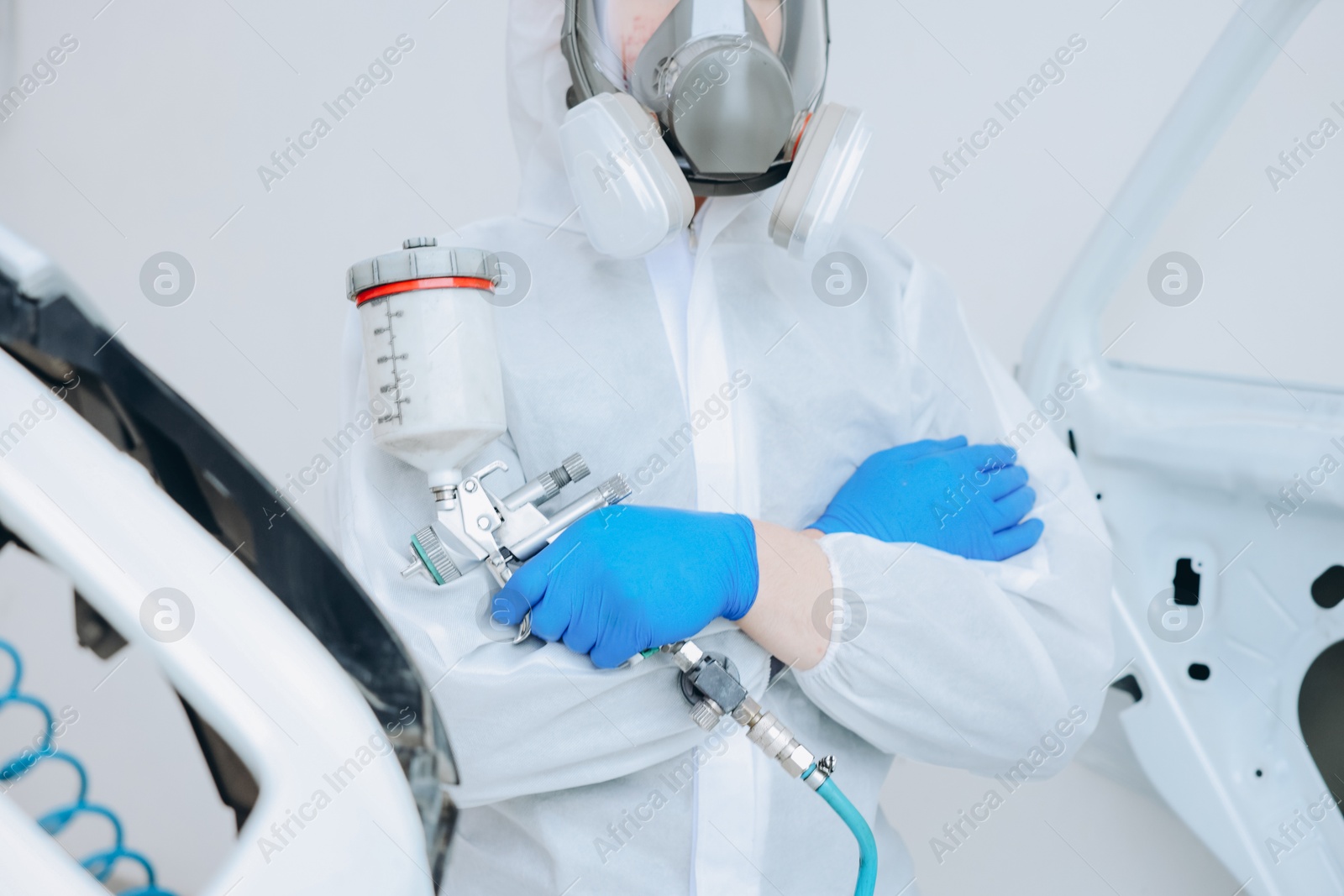 Worker with spray painting gun and car in body shop, closeup Photo of Worker with spray painting gun and car in body shop, closeup