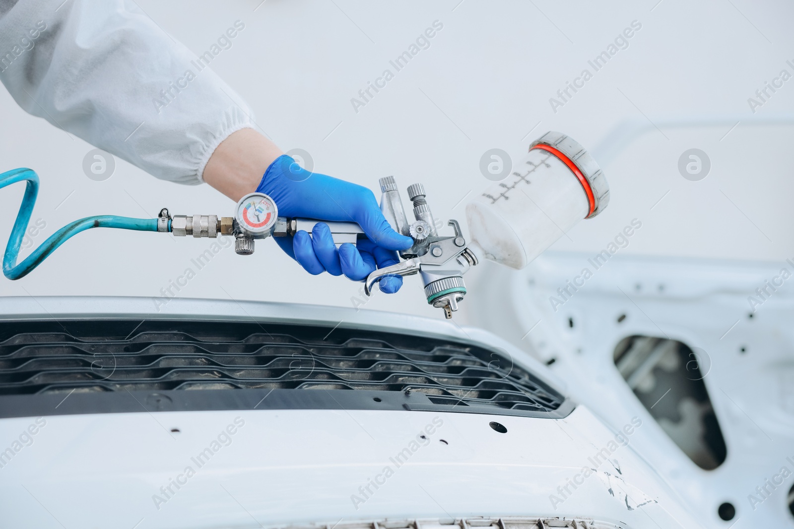 Worker painting car in body shop, closeup Photo of Worker painting car in body shop, closeup