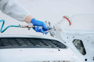 Photo of Worker painting car in body shop, closeup