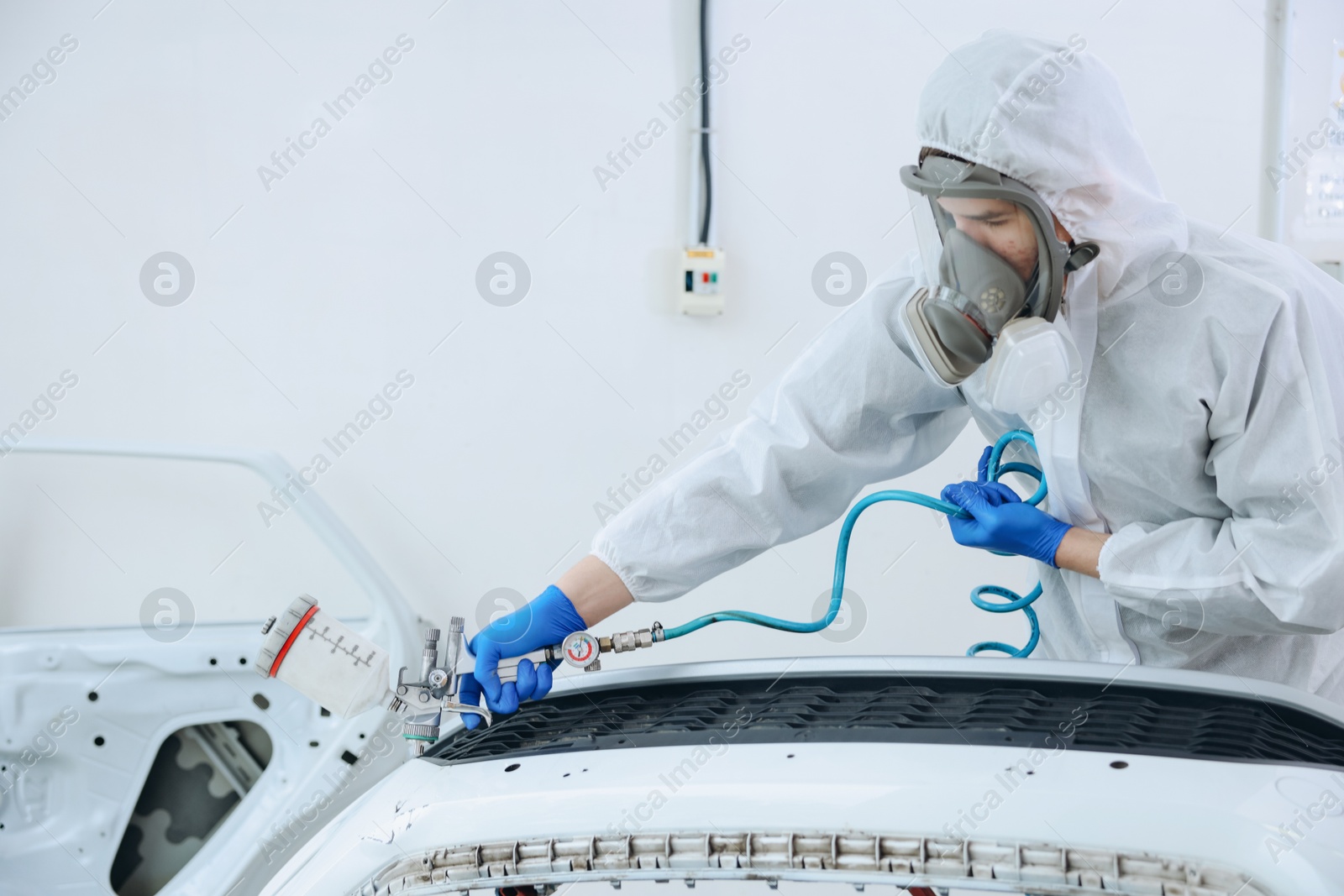 Worker spray painting car in body shop. Space for text Photo of Worker spray painting car in body shop. Space for text