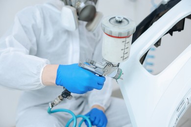 Photo of Worker painting car in body shop, closeup
