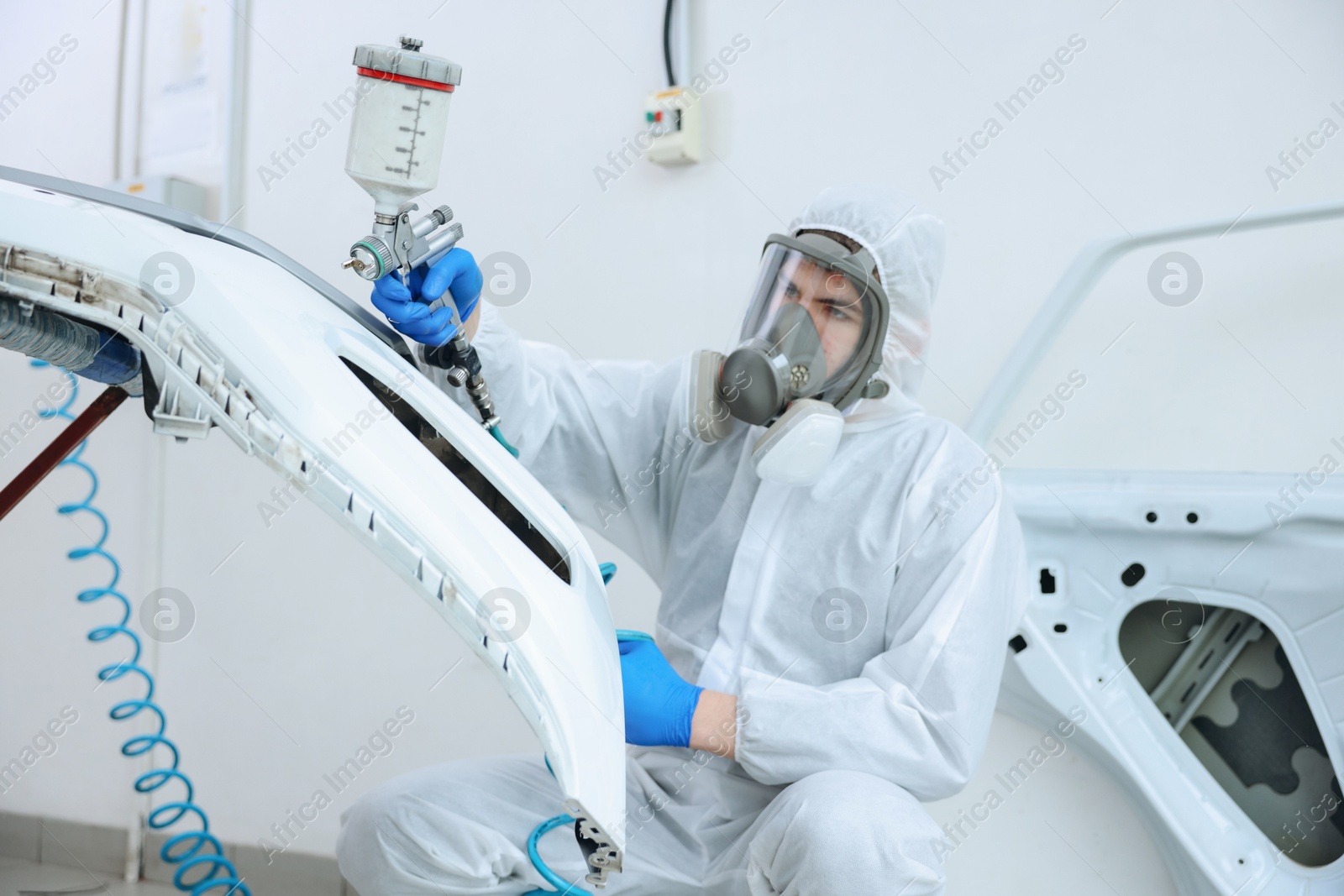 Photo of Worker spray painting car in body shop