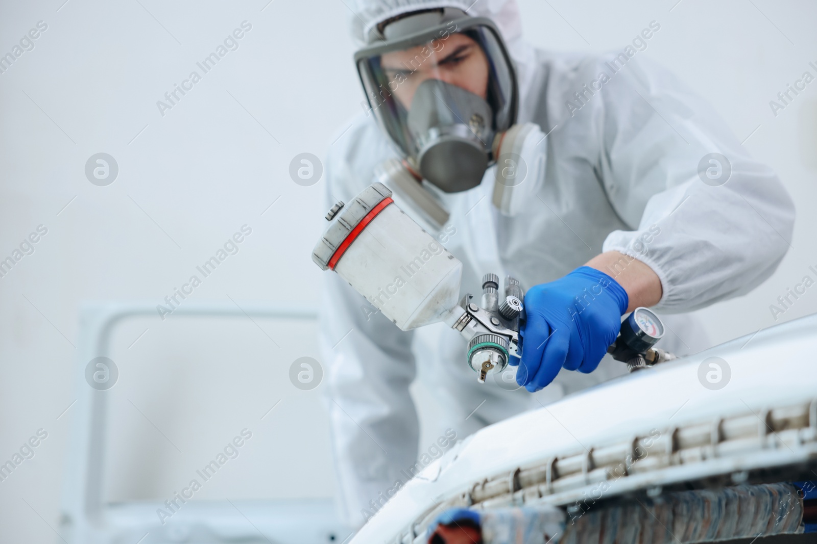 Worker painting car in body shop, selective focus Photo of Worker painting car in body shop, selective focus