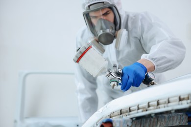 Photo of Worker painting car in body shop, selective focus