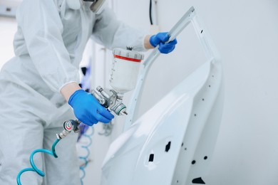 Photo of Worker painting car door in body shop, closeup