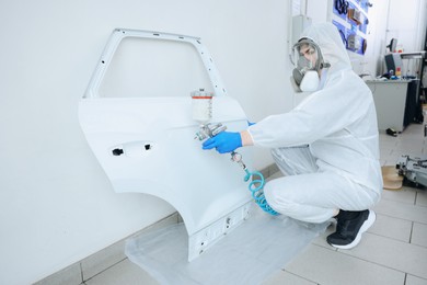 Photo of Worker painting car door in body shop