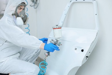 Photo of Worker painting car door in body shop