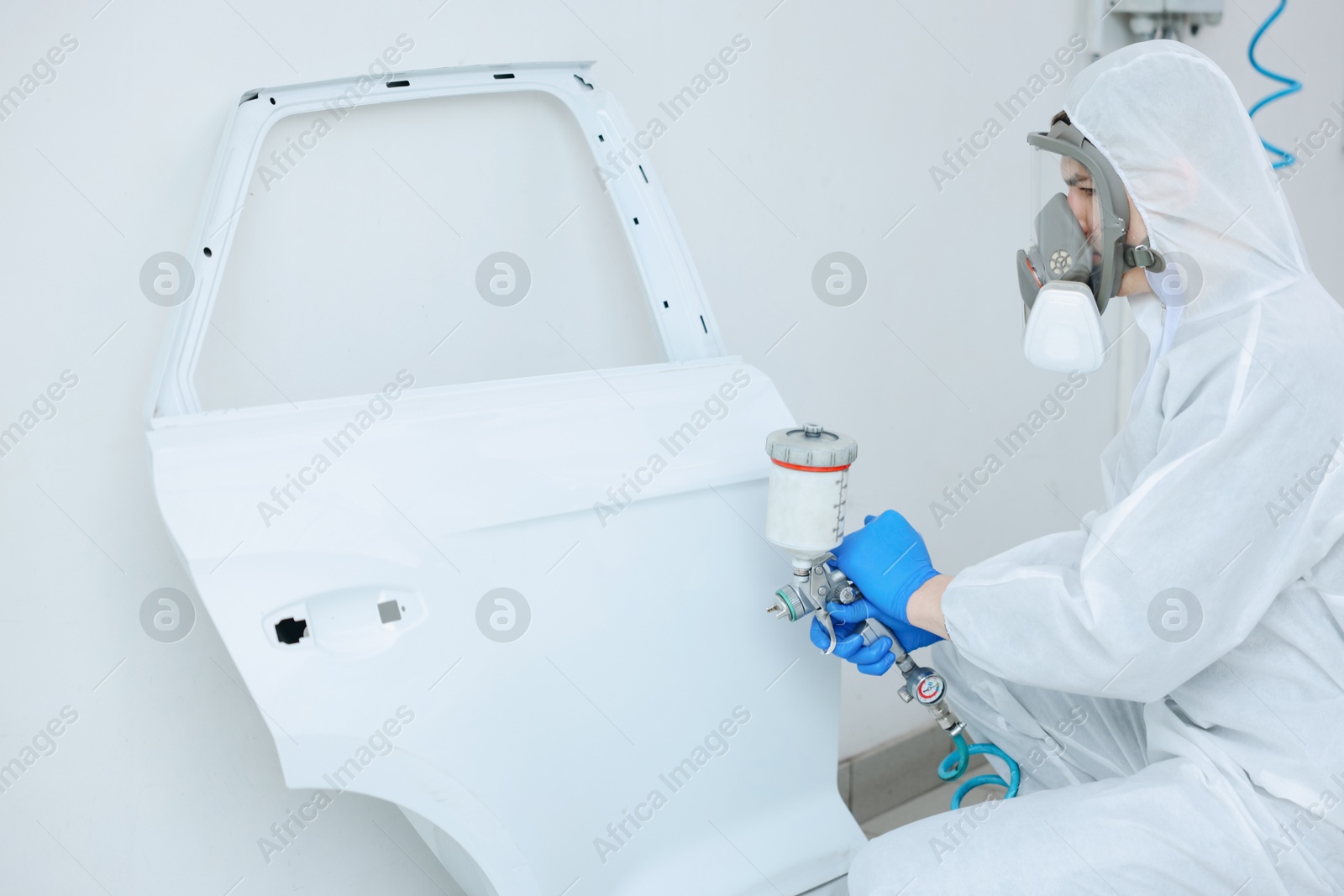 Worker painting car door in body shop Photo of Worker painting car door in body shop