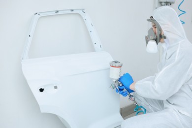 Photo of Worker painting car door in body shop