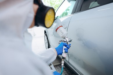 Photo of Worker painting car in body shop, closeup