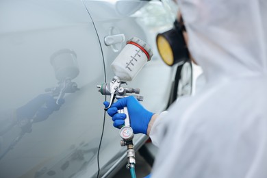 Photo of Worker painting car in body shop, closeup
