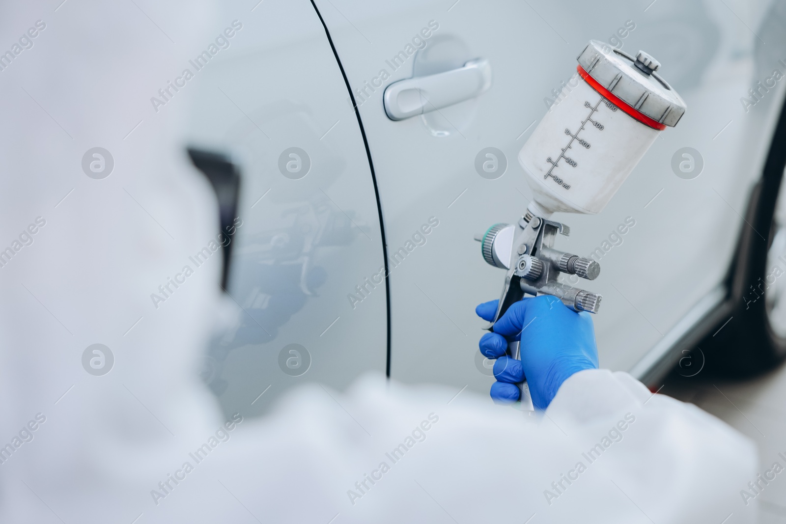 Worker painting car in body shop, closeup Photo of Worker painting car in body shop, closeup