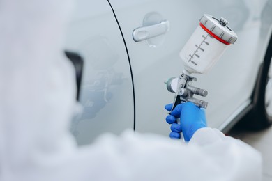 Photo of Worker painting car in body shop, closeup