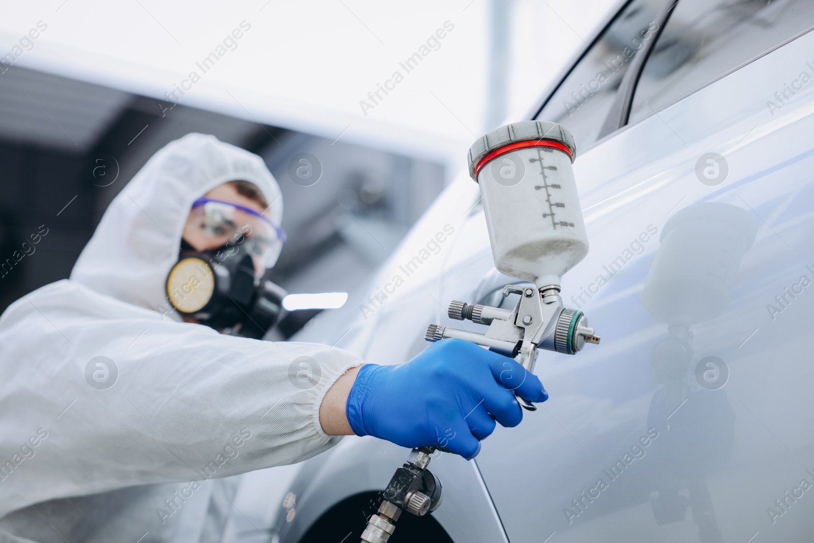 Worker painting car in body shop, selective focus Photo of Worker painting car in body shop, selective focus
