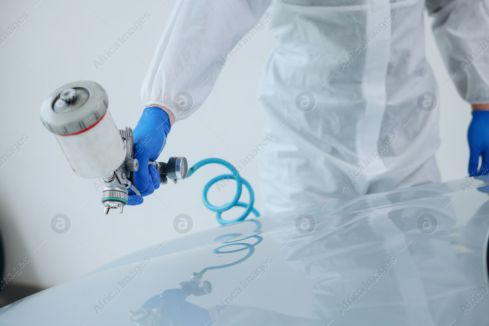 Worker painting car in body shop, closeup Photo of Worker painting car in body shop, closeup