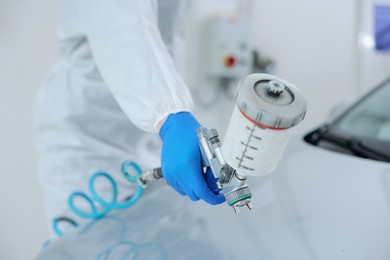 Photo of Worker painting car in body shop, closeup