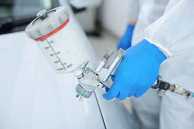 Photo of Worker painting car in body shop, closeup