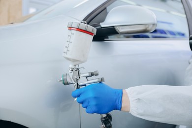 Photo of Worker painting car in body shop, closeup