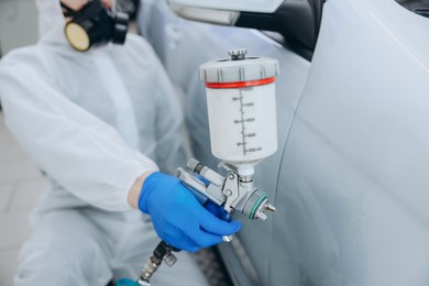 Photo of Worker painting car in body shop, closeup