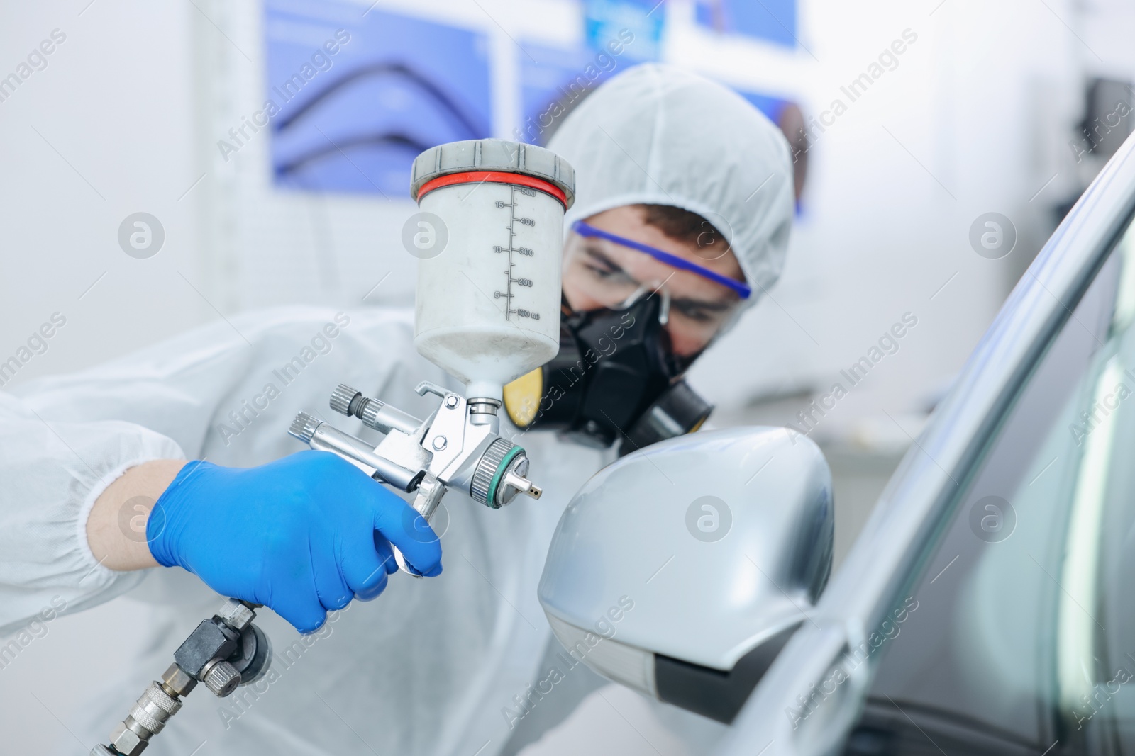 Worker painting car in body shop, selective focus Photo of Worker painting car in body shop, selective focus