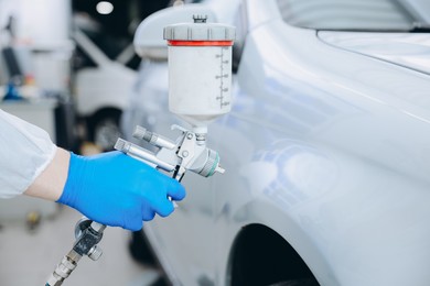 Photo of Worker painting car in body shop, closeup