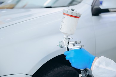 Photo of Worker painting car in body shop, closeup