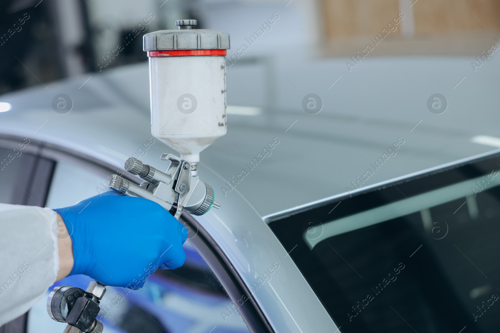 Worker painting car in body shop, closeup Photo of Worker painting car in body shop, closeup