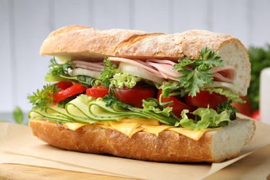 Photo of Tasty baguette sandwich with ham, cheese and vegetables on blurred grey background, closeup