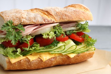 Photo of Tasty baguette sandwich with ham, cheese and vegetables on grey table, closeup