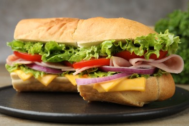 Photo of Tasty baguette sandwich with ham, cheese and vegetables on wooden table against grey background, closeup