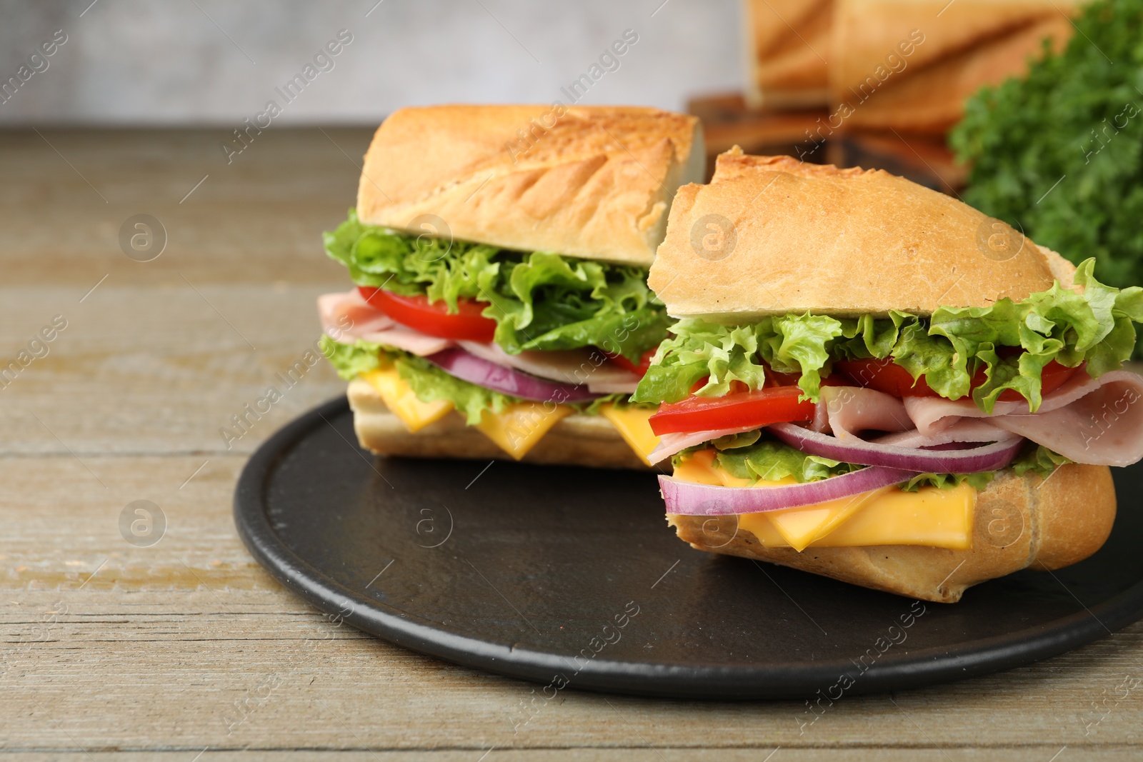 Pieces of tasty baguette sandwich with ham, cheese and vegetables on wooden table, closeup Photo of Pieces of tasty baguette sandwich with ham, cheese and vegetables on wooden table, closeup