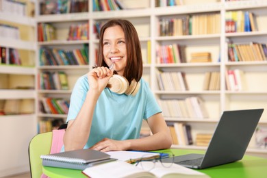 Photo of Student with laptop studying at table in library