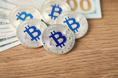 Photo of Cryptocurrency. Bitcoins and dollar banknotes on wooden table, closeup