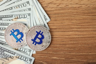 Photo of Cryptocurrency. Bitcoins and dollars on wooden table, flat lay. Space for text