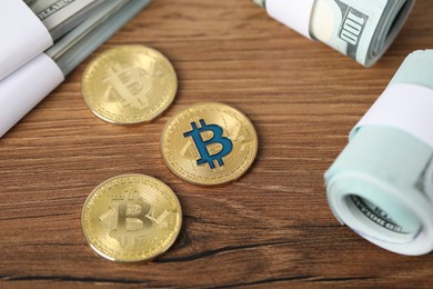 Photo of Cryptocurrency. Bitcoins and dollar banknotes on wooden table, above view