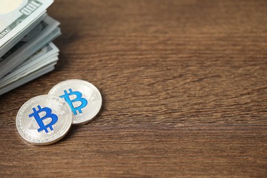 Photo of Cryptocurrency. Bitcoins and dollar banknotes on wooden table, closeup. Space for text