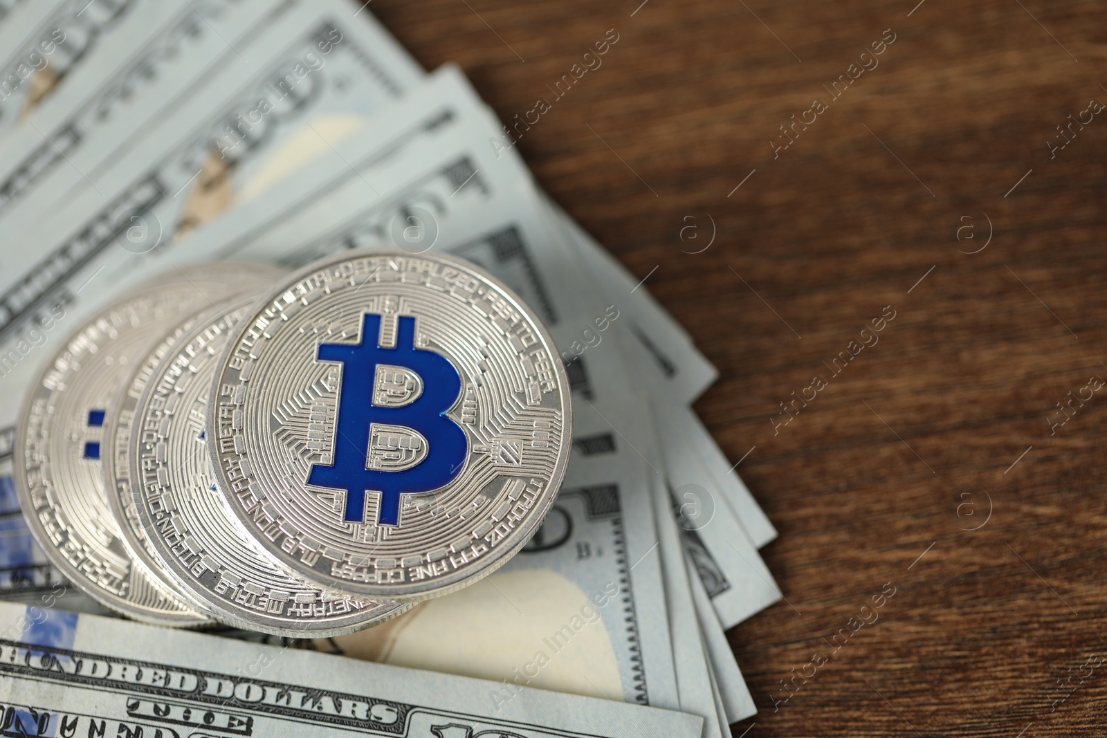 Photo of Cryptocurrency. Bitcoins and dollar banknotes on wooden table, closeup. Space for text