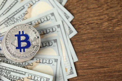 Photo of Cryptocurrency. Bitcoins and dollars on wooden table, flat lay. Space for text