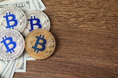 Photo of Cryptocurrency. Bitcoins and dollars on wooden table, flat lay. Space for text