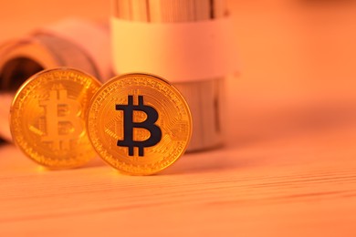 Photo of Cryptocurrency. Bitcoins and dollar banknotes on wooden table, closeup. Space for text