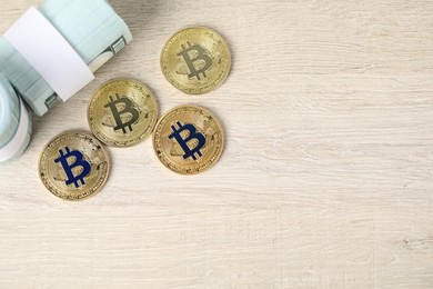 Photo of Cryptocurrency. Bitcoins and dollars on wooden table, flat lay. Space for text