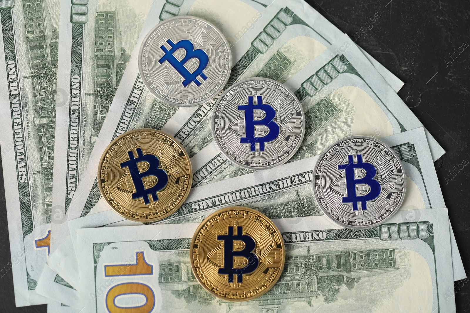 Photo of Cryptocurrency. Bitcoins and dollar banknotes on black table, flat lay