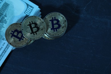 Photo of Cryptocurrency. Bitcoins and dollars on black table, flat lay. Space for text