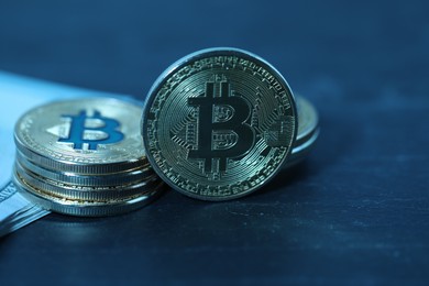 Photo of Cryptocurrency. Bitcoins and dollar banknotes on black table, closeup